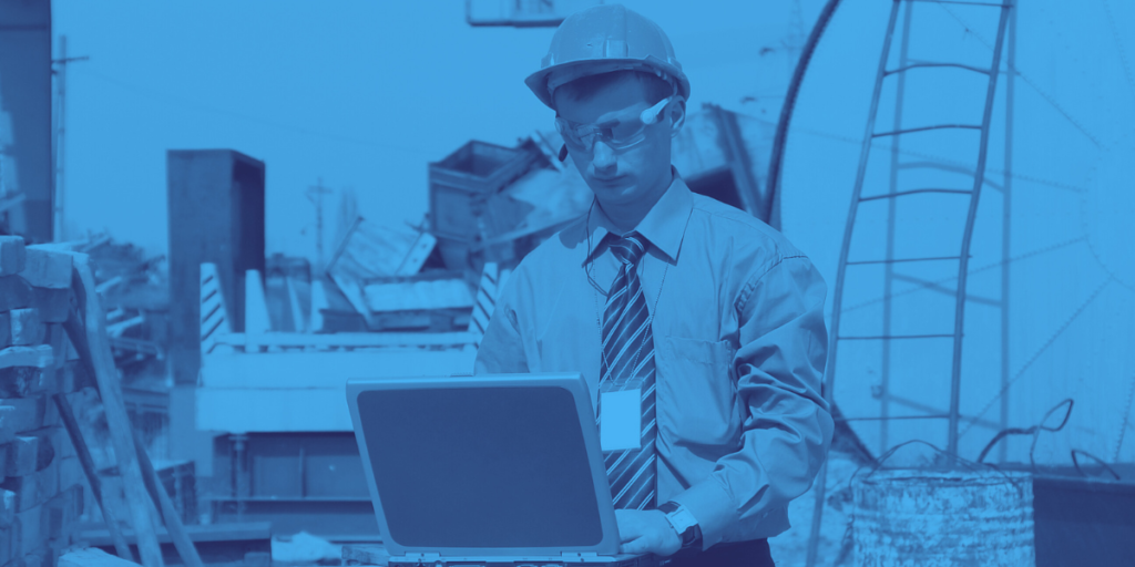 Profissional em obra utilizando laptop para monitorar sistemas de automação industrial e controle de equipamentos.